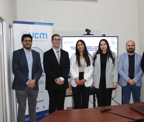 Un grupo de cinco personas se presenta en un evento formal en una sala de conferencias.