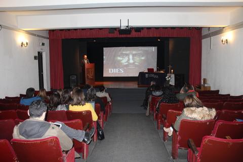 Una conferencia en un auditorio con un ponente en el escenario y una proyección al fondo.