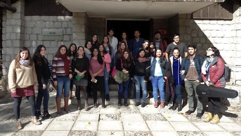 Un grupo de estudiantes posando frente a un edificio en un día soleado.