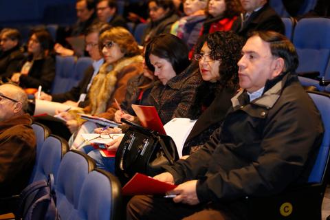 Un grupo de personas sentadas en un auditorio, concentradas en lo que parece ser una presentación o conferencia.