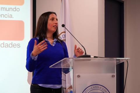 Una mujer está presentando en un evento académico con entusiasmo.