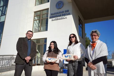 Un grupo de cuatro personas posa felices frente a la Facultad de Ingeniería de la Universidad.