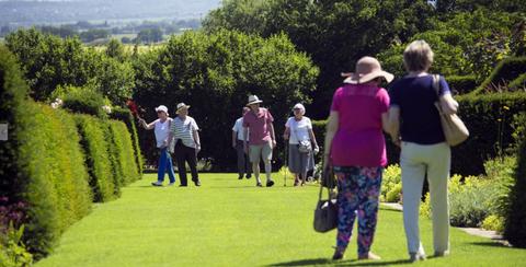 Un grupo de personas camina por un jardín en un día soleado.