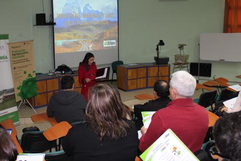 Una mujer presenta un tema relacionado con fitosanitarios frente a un grupo de personas en un aula.