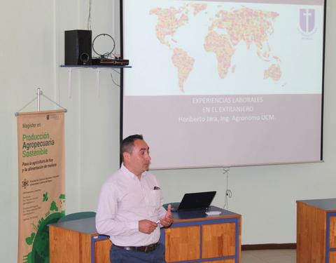Un hombre presenta información sobre experiencias laborales en el extranjero frente a una pantalla con un mapa mundial.