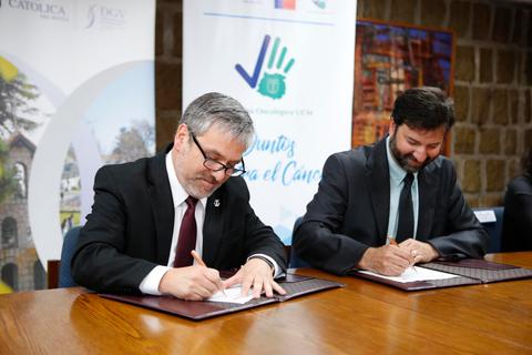 Dos hombres firmando un acuerdo en una mesa.