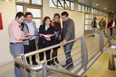 Un grupo de cinco personas revisa libros en un pasillo moderno.
