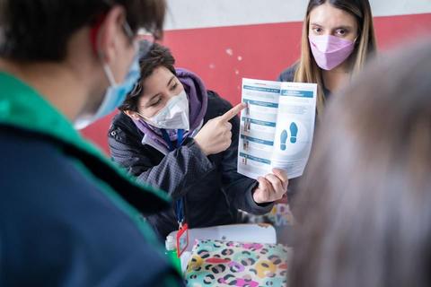 Un grupo de personas discutiendo sobre un documento mientras una de ellas señala información en la hoja.