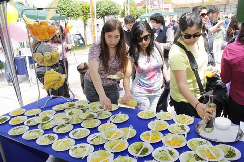 Un grupo de personas sirve ensaladas en un evento al aire libre.