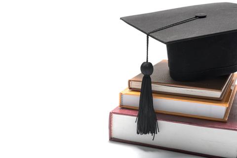 Una gorra de graduación está colocada sobre una pila de libros.