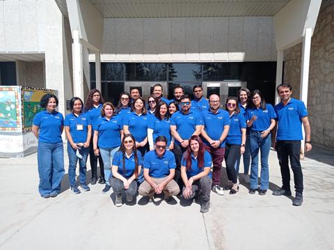 Grupo de personas sonrientes posando frente a un edificio.