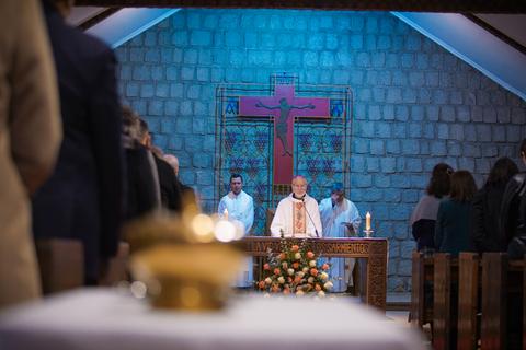 Una ceremonia religiosa en una iglesia chilena con un altar decorado y un sacerdote en acción.