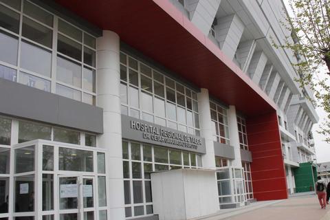 Edificio moderno de un hospital con grandes ventanales y acceso principal visible.