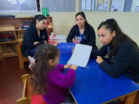 Un grupo de educadoras está interactuando con una niña en un ambiente de aprendizaje.