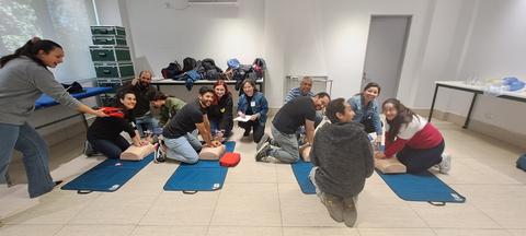 Un grupo de personas participa en una sesión de formación de reanimación cardiopulmonar en un aula.