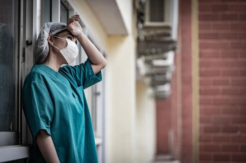 Una profesional de la salud parece estar reflexionando en un entorno urbano.