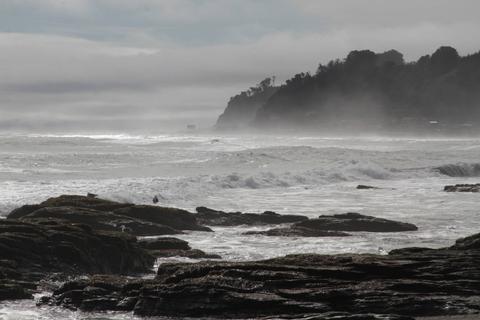 Una vista de la costa con rocas y el mar agitado bajo un cielo nublado.