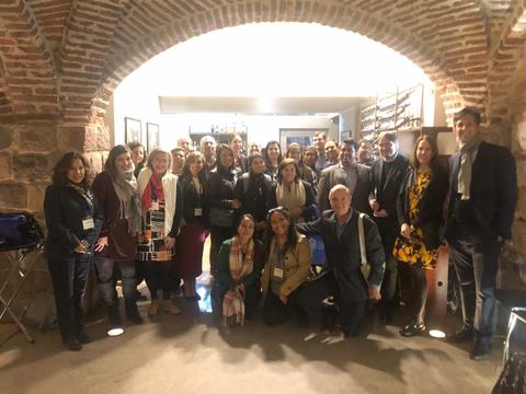 Un grupo de personas posando en un evento social dentro de un espacio con arcos de ladrillo.