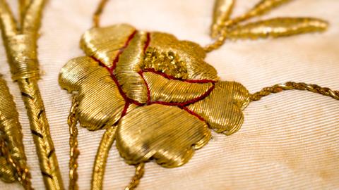 Una delicada bordado de una flor en hilos dorados.