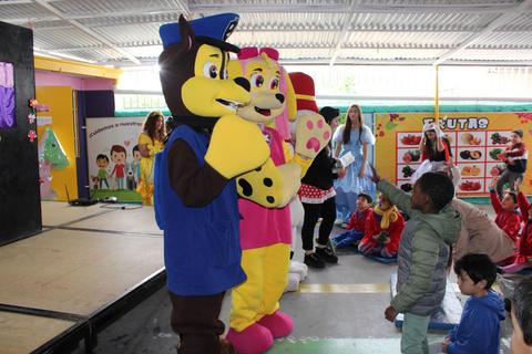 En la imagen se pueden ver a dos personajes disfrazados en un evento infantil, rodeados de niños emocionados.