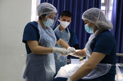 El grupo de profesionales de la salud está realizando un procedimiento médico con un paciente en un entorno clínico.