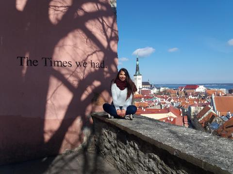 Una mujer sentada en una muralla con vista a una ciudad antigua.