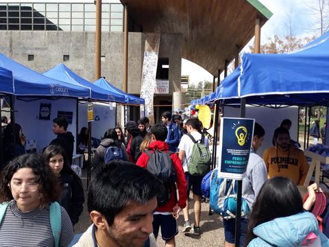 Una feria en un campus universitario con estudiantes y varias carpas azules.