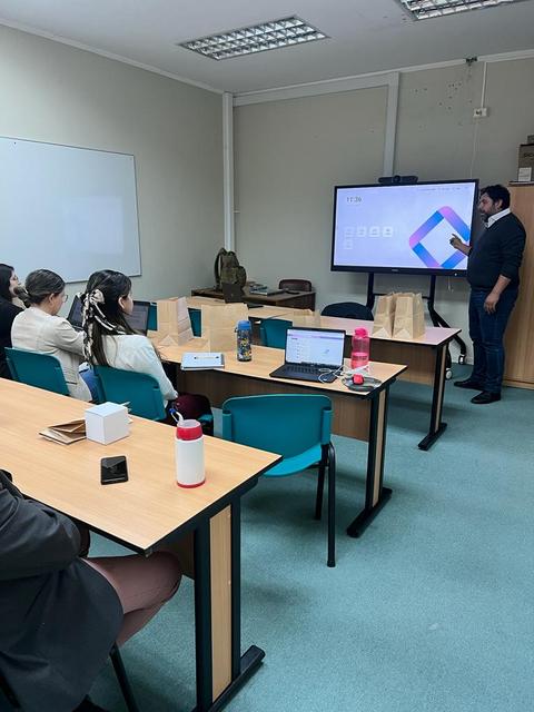 Una presentación en un aula con un ponente mostrando una pantalla mientras los asistentes lo observan.