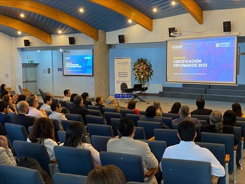 Una ceremonia de entrega de certificados de diplomados en un auditorio lleno de asistentes.