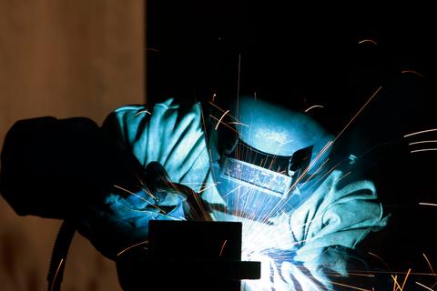 Un soldador trabaja en un metal mientras emite chispas brillantes.