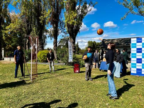Un grupo de personas juega al baloncesto al aire libre en un día soleado.
