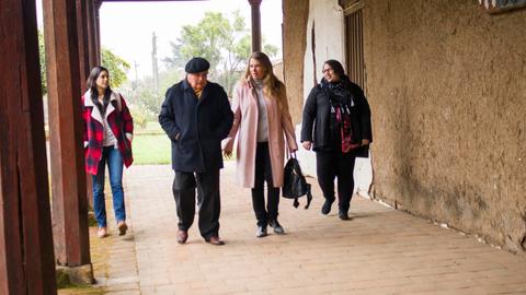 Cuatro personas caminan juntas por un pasillo al aire libre en un día nublado.