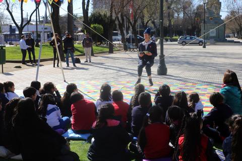 Un narrador cuenta historias a un grupo de niños sentados en un parque.