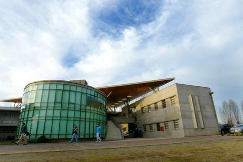 Edificio moderno con grandes ventanales y detalles arquitectónicos en un entorno natural.