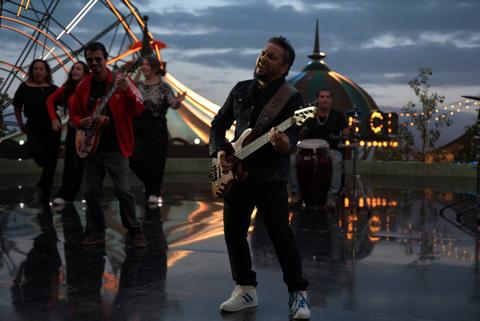 Un grupo de personas están tocando música y bailando al aire libre durante el atardecer.