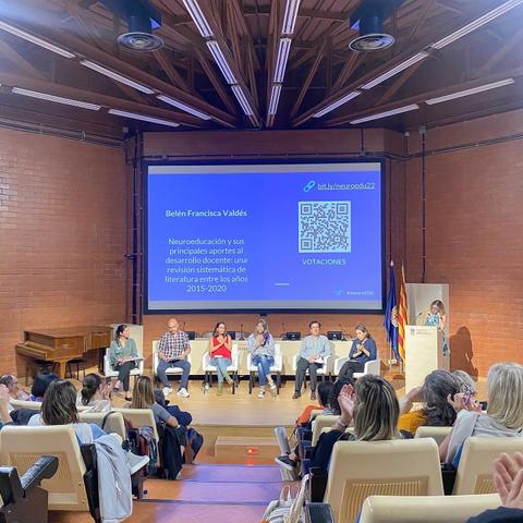 Una conferencia en un auditorio donde varios ponentes están presentando sobre neuroeducación frente a un público atento.