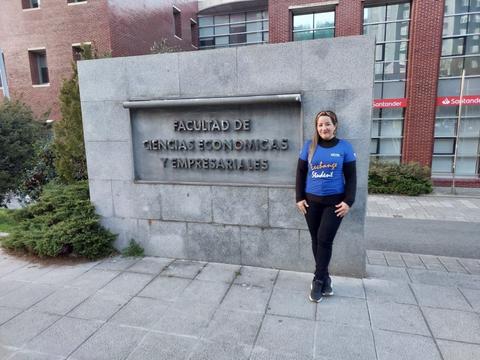Una persona posa frente a un letrero de la Facultad de Ciencias Económicas y Empresariales.