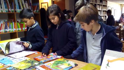 Un grupo de niños está examinando libros en una biblioteca.