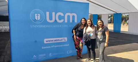 Tres personas posan frente a un fondo con el logotipo de la Universidad Católica del Maule.