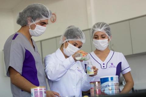 Estudiantes en un laboratorio realizando experimentos con recipientes de muestra.