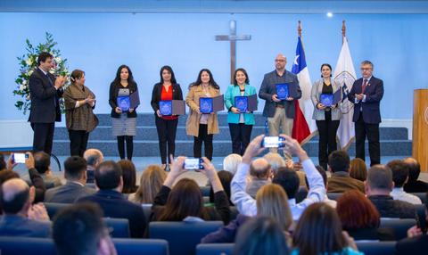 Ceremonia de premiación en un auditorio con varias personas recibiendo diplomas.