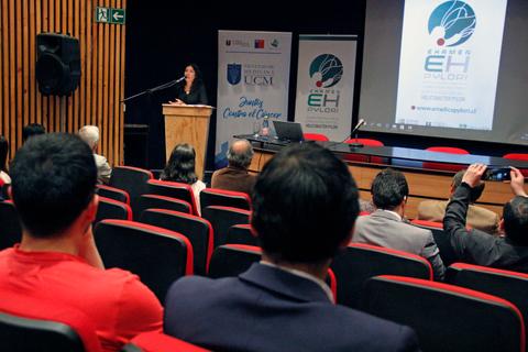 Una presentación en un auditorio con una ponente en el estrado y un público atento.