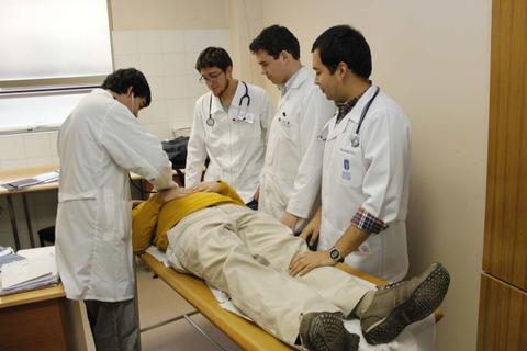 Cuatro médicos están realizando un procedimiento en un paciente recostado en una camilla.