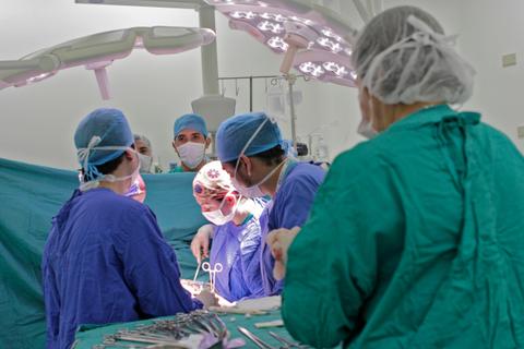 Un grupo de cirujanos y personal médico trabajando en una cirugía en un quirófano.