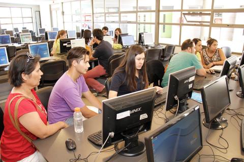 Un grupo de personas trabajando en computadoras en un aula de clases.