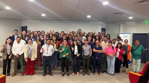 Un grupo grande de personas está sonriendo y saludando en un evento en grupo.