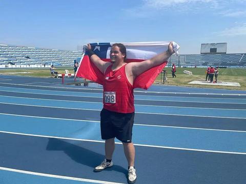 Un atleta celebra con una bandera chilena en una pista de atletismo.