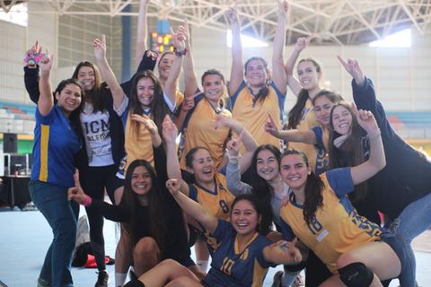 Un grupo de jóvenes sonrientes celebra en el gimnasio con gestos de victoria.