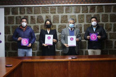 Cuatro personas posan en un ambiente interior sosteniendo documentos y con mascarillas.