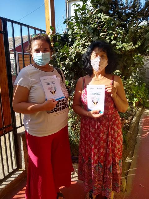 Dos mujeres sosteniendo documentos mientras posan en un entorno al aire libre.